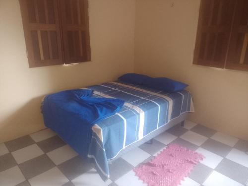 a bedroom with a bed with blue sheets and a pink rug at pousada Rios in Belém