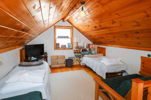 a attic room with two beds and a tv at Lake Christopher Cabin in Bryant Pond