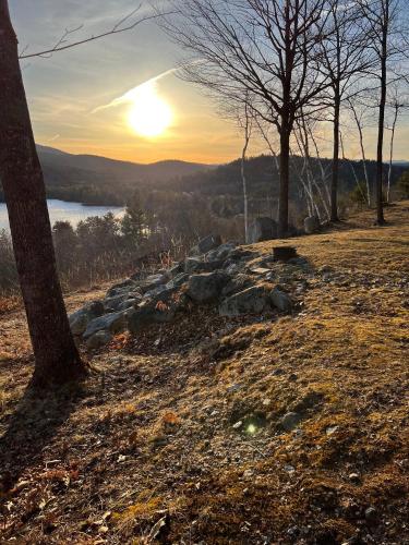 a sunset over a field with trees and a rock wall at Lake Christopher Cabin in Bryant Pond