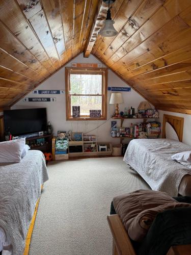 a attic room with two beds and a television at Lake Christopher Cabin in Bryant Pond