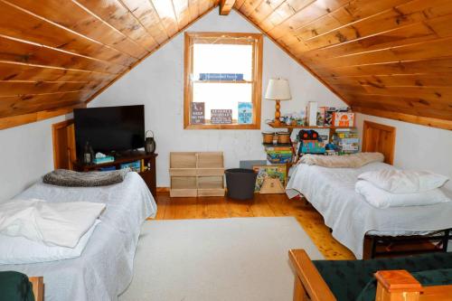 a attic room with two beds and a television at Lake Christopher Cabin in Bryant Pond