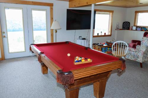 a red pool table in a living room with a tv at Lake Christopher Cabin in Bryant Pond