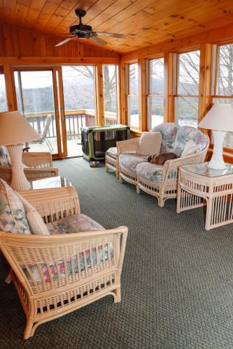 a living room with wicker chairs and tables and windows at Lake Christopher Cabin in Bryant Pond