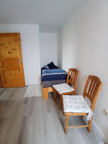 a room with two chairs and a bed and a door at Ferien- und Pferdehof Egelkraut "Feriendomizil am Meer" in Wangerland