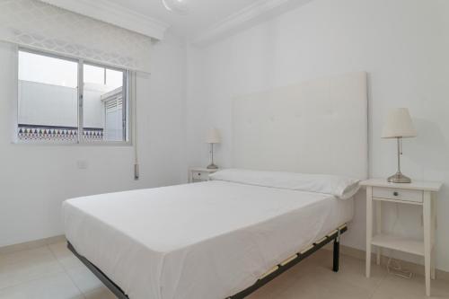 a white bedroom with a large bed and a window at Casa Ricardo in Barbate