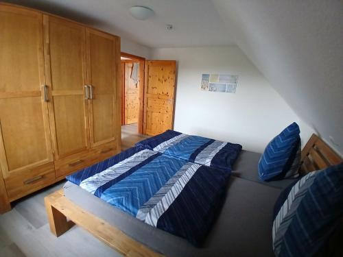 a bedroom with a blue bed and wooden cabinets at Ferien- und Pferdehof Egelkraut "Feriendomizil am Meer" in Wangerland