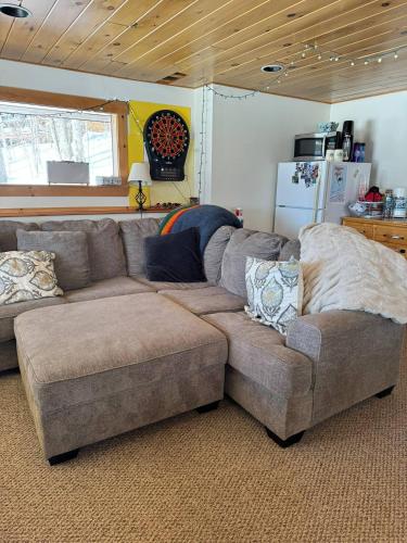 a living room with a sectional couch and a refrigerator at Lake Christopher Cabin in Bryant Pond