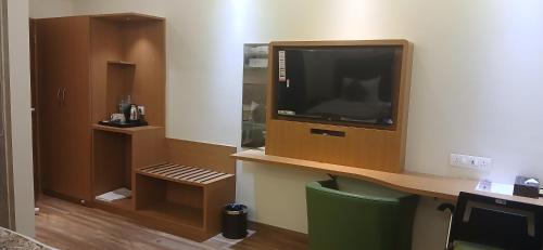 a room with a tv and a desk with a chair at Shine Hospitality Premium in Mumbai