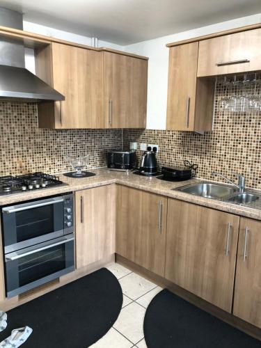a kitchen with wooden cabinets and a sink at Home Away from Home in Milton Keynes