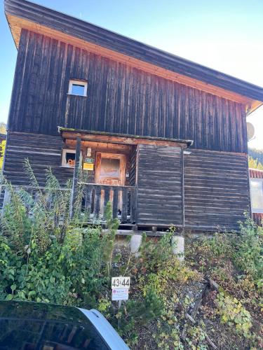 an old wooden house with a sign in front of it at Feriendorf Tauerngast in Hohentauern