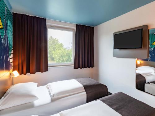 a hotel room with two beds and a flat screen tv at B&B Hotel Hannover-Lahe in Hannover