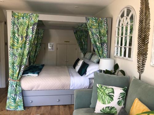 a bedroom with a bed with curtains and a couch at The Nest Danehill in Haywards Heath