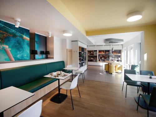 un restaurante con un banco verde, mesas y sillas en B&B Hotel Jena, en Jena