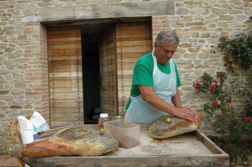 a man is making bread on a table at Agriturismo Biologico Villa Rosa in Monte Guiduccio