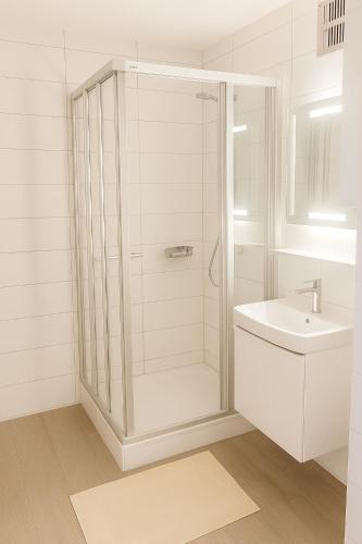a white bathroom with a shower and a sink at Ferienstube alte Teestube Norderney in Norderney
