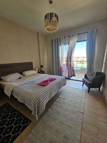 a bedroom with a bed and a chair and a window at فيلا Azha بالعين السخنه للعائلات in Ain Sokhna