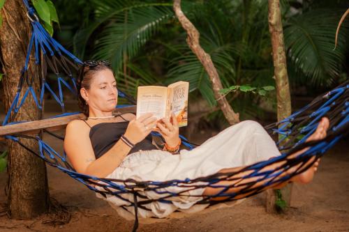 a woman laying in a hammock reading a book at woodland sanctuary in Habarana