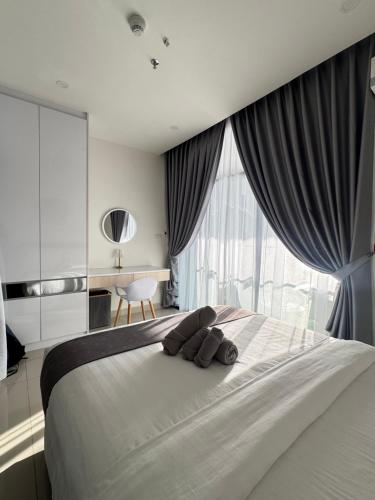 a large bed with a teddy bear laying on it at The Shore Kota Kinabalu by Ems Executive Suites Seaview in Kota Kinabalu