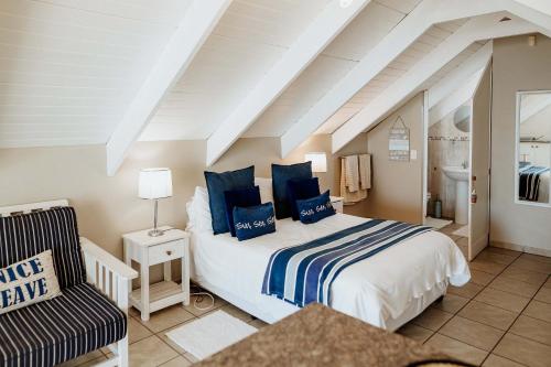 a bedroom with a bed with blue pillows and a chair at Paters Nessie in Paternoster