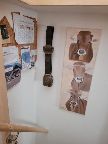 a wall with pictures of cows and a watch at Bergwiese Mit Balkon in Nesselwängle