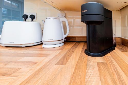 two coffee machines sitting on a wooden floor at Fresh, stylish apartment in Sherborne Saint John