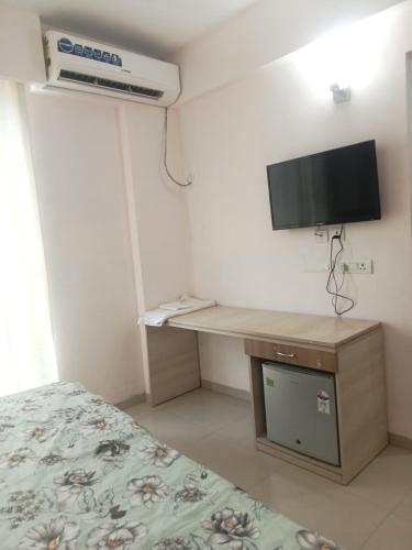 a bedroom with a bed and a desk with a television at Vrindavan Omex in Vrindāvan