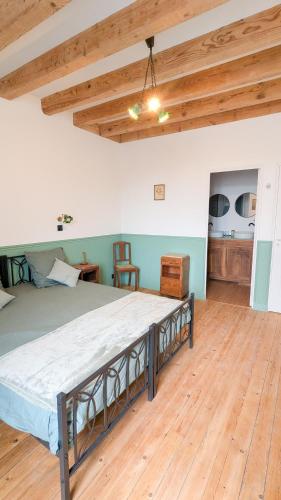 a large bed in a room with a wooden floor at Auberge de la Belette Cendrée in Saint-Léger-sous-Beuvray