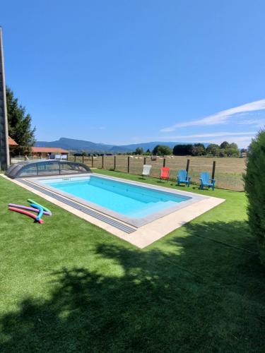 une piscine dans une cour herbeuse avec des chaises autour dans l'établissement Chambre d'hôtes, coquelicot, le petit cocon d'auré, à Corbelin