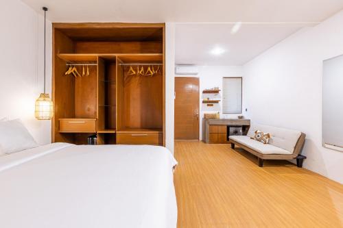 a white bedroom with a bed and a couch at SNUG Kuta in Kuta