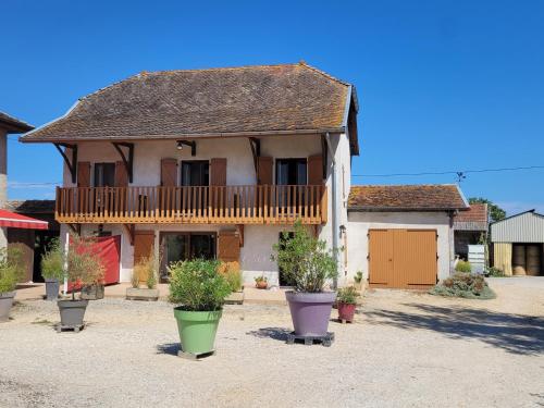 une grande maison avec un balcon et des plantes en pot dans l'établissement Chambre d'hôtes, coquelicot, le petit cocon d'auré, à Corbelin