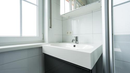 a white bathroom with a sink and a window at Nethehuis in Kasterlee