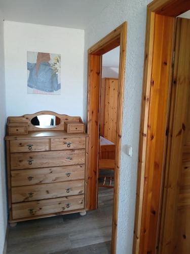 a bedroom with a wooden dresser and a mirror at Ferien- und Pferdehof Egelkraut "Feriendomizil am Meer" in Wangerland