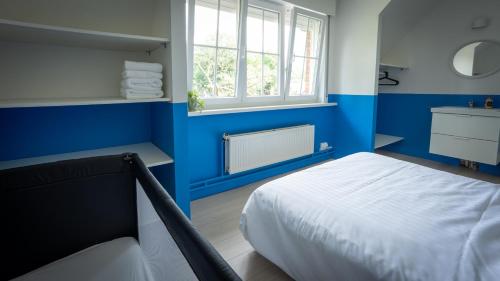 a blue bedroom with a bed and a window at Nethehuis in Kasterlee