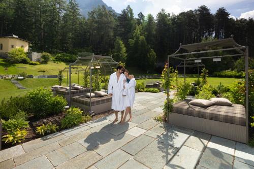 a bride and groom standing in front of a garden at QC Grand Hotel Bagni Nuovi in Bormio
