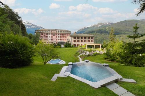 a large building with a swimming pool in a yard at QC Grand Hotel Bagni Nuovi in Bormio