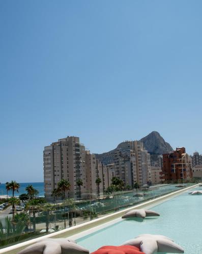 a swimming pool with umbrellas next to a city at AR Diamante Beach & SPA Hotel 4 SUP in Calpe
