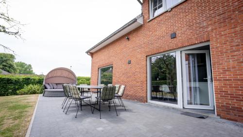 a patio with a table and chairs next to a brick building at Nethehuis in Kasterlee