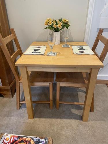 a wooden table with two chairs and a vase of flowers at Cosy Country Cottage in Bethersden