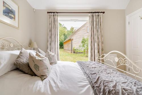 a white bed in a bedroom with a window at Cosy Country Cottage in Bethersden