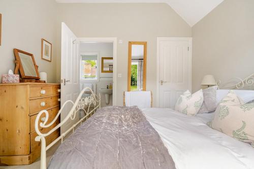 a bedroom with a white bed and a dresser at Cosy Country Cottage in Bethersden