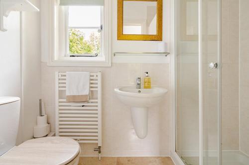 a white bathroom with a sink and a shower at Cosy Country Cottage in Bethersden