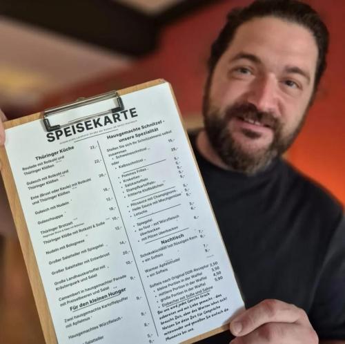 a man holding a menu in his hand at Ferienwohnung - in Hildebrandts Landhotel in Klettbach