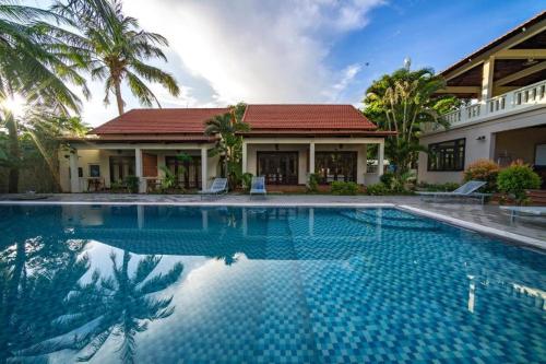 a swimming pool in front of a house at Hula Hula Seafront Phu Quoc in Phu Quoc