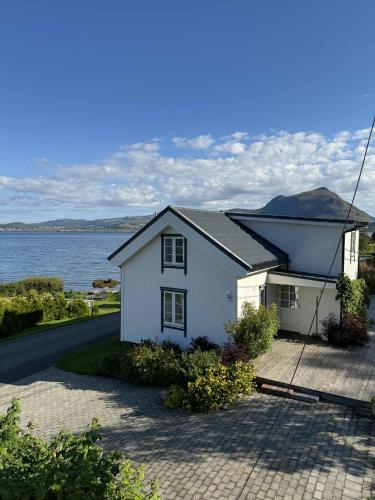 Traditional Nordlandshus in Lofoten - Sea and Mountain View في Vestvågøya: بيت ابيض بجانب تجمع المياه