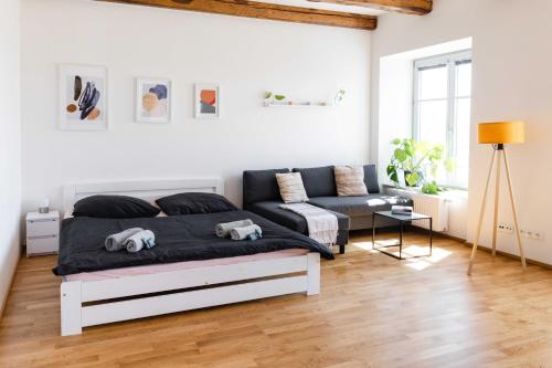 a white bedroom with a bed and a couch at Studio K2 in Brno