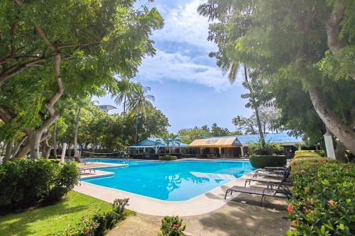 a large swimming pool with benches and trees at Puerto Azul 153 in El Roble