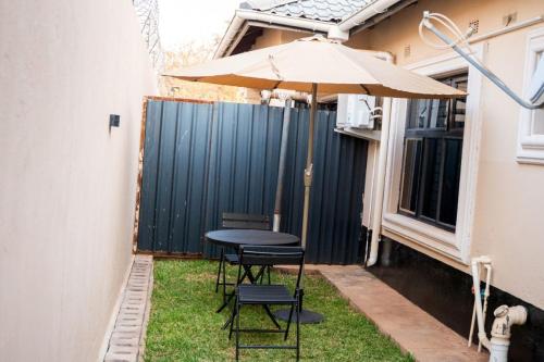 a table and chairs with an umbrella in the yard at RJV Apartments, Meanwood Ibex Hill, Lusaka in Lusaka