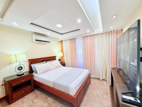 a bedroom with a bed and a flat screen tv at Sol y Confort Suites in Machala