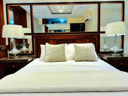 a bedroom with a large white bed with two lamps at Sol y Confort Suites in Machala
