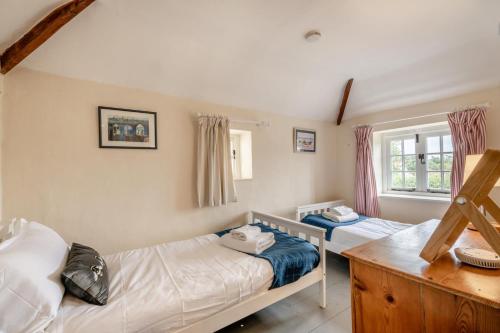 een slaapkamer met twee bedden en een raam bij Postmill Cottage in Burnham Market